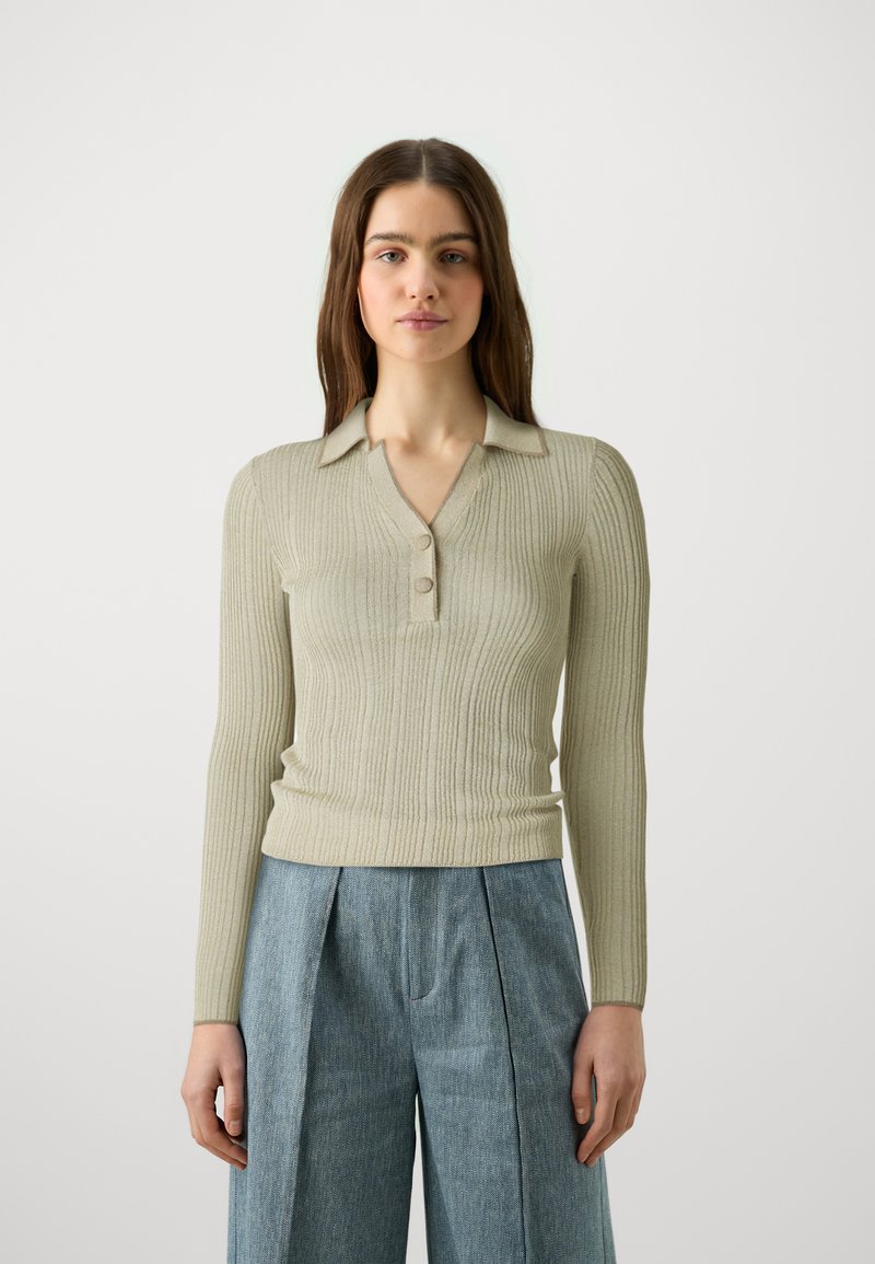 Pulover cu mâneci lungi, ușor nervurat, de culoare bej deschis, cu guler și trei nasturi. Asortat cu pantaloni din denim texturat, largi.