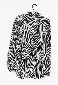 Chemise à manches longues imprimé zèbre noir et blanc, en tissu léger, avec col boutonné et fentes latérales à l'ourlet.