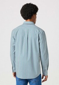 Koszula z długim rękawem w niebiesko-zieloną krate, z szwem wzdłuż pleców, zapinanymi mankietami i kołnierzykiem; wykonana z lekkiej mieszanki bawełny.