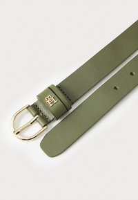 Olive green leather belt with a gold-tone metal buckle and logo accent. Smooth texture, multiple adjustment holes for sizing.