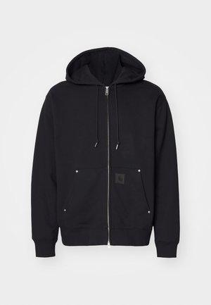 Zwarte zip-up hoodie gemaakt van zachte stof. Beschikt over een grote capuchon, voorzakken, zilveren hardware en een vierkante logopatch op de linker zak.