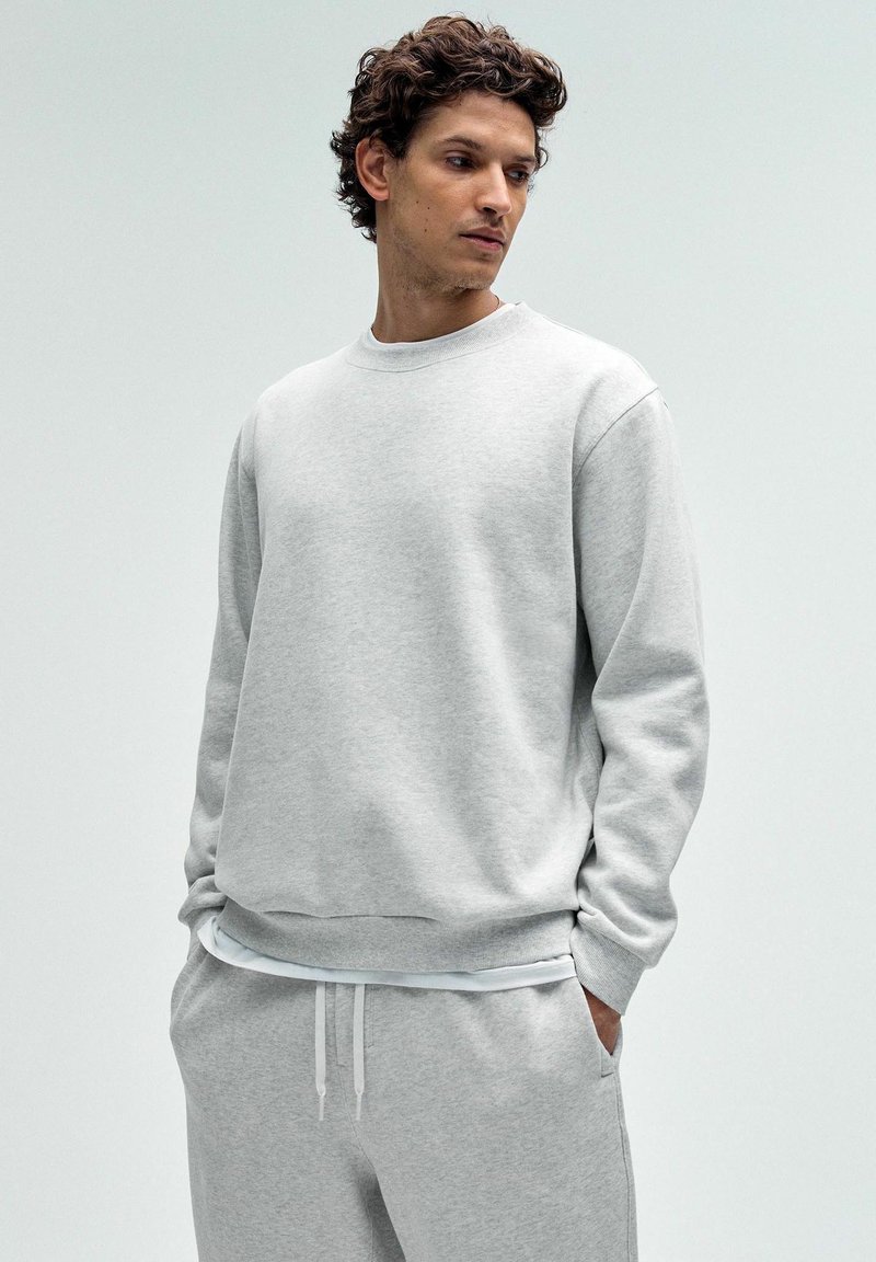 Helehall sweatshirt ümmarguse kaelusega, pikkade varrukatega ja soonikkäärtega. Pehme tekstuur, koos sobivate helesiniste sviitritega.