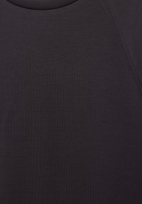 Gros plan sur un tissu gris foncé montrant une texture fine et des coutures le long de la zone des épaules d'un vêtement.