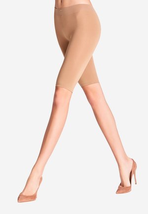 Leggings nus mi-mollet avec une texture lisse et extensible et une taille élastique, assortis à des escarpins beiges à talons pointus.