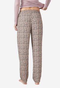 Pantalons de pyjama à imprimé floral en tissu léger, à jambes larges et avec une taille élastique. Présentent des fleurs roses sur un fond noir.