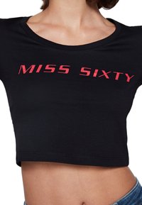 Czarny bawełniany crop top z okrągłym dekoltem i krótkimi rękawami. Z przodu znajduje się napis "MISS SIXTY" w odważnych czerwonych literach.