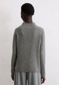 Grau melierter Wollpullover mit hohem Kragen, überschnittenen Schultern und lockerem Schnitt. Verfügt über eine weiche Textur und einen leicht geschwungenen Saum hinten.