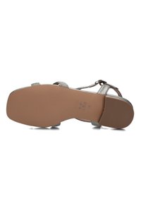 Zilveren metallic sandaal met gevlochten banden, een flexibele rubberen zool en een opvallende lage hak. De onderkant heeft een gestructureerd patroon voor grip.