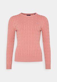 Pull rose clair en maille torsadée avec manches longues, encolure ronde et poignets et ourlet côtelés. Présente un petit logo sur la poitrine.