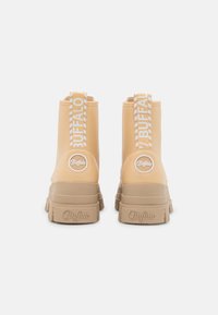 Beżowe botki typu ankle w stylu Buffalo, o gładkim wykończeniu, wsuwanym designie, grubej podeszwie oraz kontrastowej, w kratkę pętli do zakupu. Logo marki na pięcie.