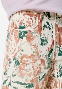 Bloemmotief broek met een crèmekleurige basis en aardse roze en groene ontwerpen, gemaakt van textuurstof, met voorzakken.