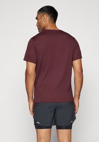 Burgunderfarget t-skjorte med korte ermer og rund hals. Mykt stoff, glatt tekstur. Brukes sammen med mørke shorts med subtile detaljer.