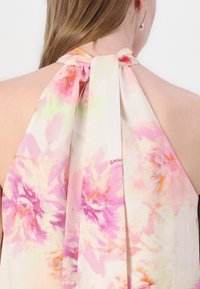Blomstret halterneck-top i blødt, let stof med nuancer af pink og orange. Afsluttes med en sløjfe bagpå.