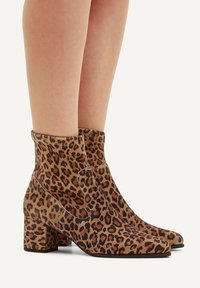 Bottes chelsea imprimé léopard avec une finition en suède texturé, dotées d'un talon bloc et d'un design ajusté qui atteint le mollet.