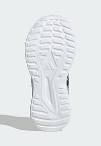 White rubber sneaker sole with textured grip patterns and ridges; features a central groove for flexibility and a logo on the side.