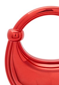 Rød plastik håndtaske med et buet håndtag og en sfærisk detalje, glat overflade og en blank finish.