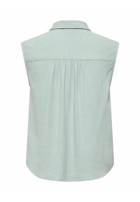 Blouse vert clair sans manches avec col, empiècement au dos et détail de tissu froncé sous l'empiècement.