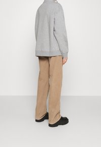 Grå sweatshirt med hög krage, lös passform. Beiga kordflossbyxor med strukturerad yta. Svarta kraftiga skor fulländar outfiten.