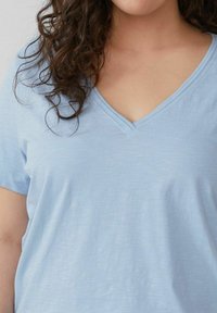 Lichtblauwe V-hals T-shirt, gemaakt van zachte, lichte stof. Heeft korte mouwen en een relaxte pasvorm met een gladde textuur.