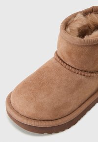 Bársonyos barna bokacsizma kerek orral, steppelt részletekkel és puha belső béléssel a melegségért. Gumitalp a tapadásért.