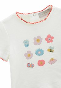 T-shirt blanc avec un col festonné rouge présentant neuf fleurs colorées dessinées en style cartoon, une abeille et un papillon imprimés à l'avant.