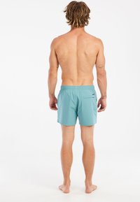 Pánske plavky v svetlomodrej látke. Obsahuje elastický pás a zadnú kapsu so chlopňou. Materiál je hladký a ľahký.