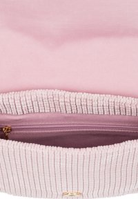 Růžová texturovaná vnitřní část látkové tašky s žebrovaným okrajem, vybavená zlatým zipem a hladkou podšívkou. Uzavírá se kulatým kovovým drukem.