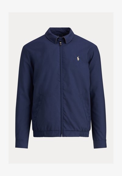 Marineblaue Jacke mit Reißverschluss, Stehkragen, elastischem Bund, Seitentaschen und kleinem weiß besticktem Polo-Spieler-Logo auf der Brust.