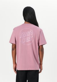 Roze katoenen t-shirt met een cirkelvormig "Santa Cruz Skateboards" logo in het wit op de achterkant. Korte mouwen en een relaxed fit ontwerp.