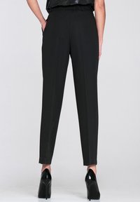 Czarne, zwężane spodnie z wysokim stanem, z podwójnymi bocznymi kieszeniami i gładką fakturą. W zestawie z błyszczącymi czarnymi szpilkami.