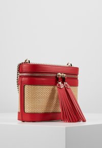 Czerwona torebka na ramię z naturalnej skóry i plecionego słomy z metalowymi, srebrnymi elementami, podwójnym suwakiem i ozdobnym chwostem. Prostokątny kształt z fakturowanymi detalami.