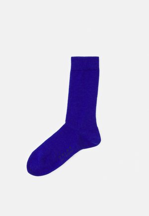Paarse sok met ribbelrand en een gladde textuur. Bevat het logo nabij de teen in het zwart. Standaardlengte, effen kleur zonder patronen.