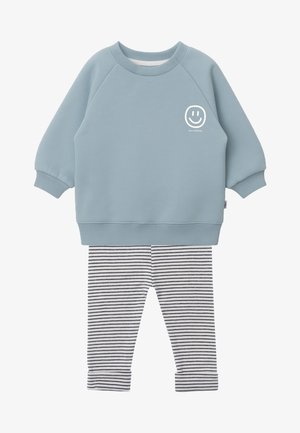 Helles blaues Sweatshirt mit Rundhalsausschnitt und lächelndem Gesichtsgrafik; kombiniert mit gestreiften Leggings in Weiß und Marineblau. Weicher Stoff, gerippte Bündchen.