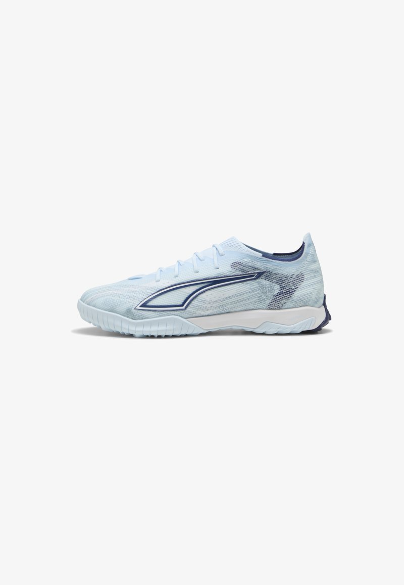 Chaussure de sport bleu clair à profil bas, semelle texturée, lacets et détail de bande courbée bleu foncé sur le côté.