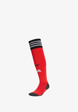 Rote knielange Socke mit schwarz-weißen gestreiften Bündchen, verstärktem Fersen- und Zehenbereich, mit dem Markenlogo in Schwarz und Weiß auf der Vorderseite.