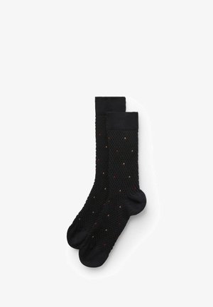 Chaussettes noires en tricot présentant un motif texturé avec des points multicolores en rouge et beige, finies par un haut en noir uni.