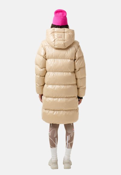 Beige skinnende dunjakke med hætte, quiltet design og vandrette striber. Sammen med mønstrede leggings og en lys pink hue.