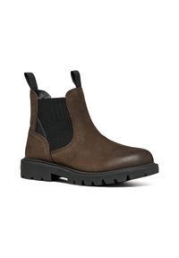 Bottines Chelsea en cuir marron avec des panneaux élastiques noirs sur les côtés, des languettes de traction et une semelle épaisse à crampons noirs, présentées sur un fond blanc.