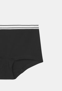 Gli slip boxer neri in cotone presentano un cinturino a righe bianche in contrasto. Il tessuto appare liscio con bordi cuciti.
