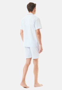 Pijamas cortos de algodón con un patrón de cuadros azul claro, mangas cortas y ribetes rojos en el cuello y los bolsillos.