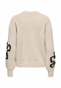 Cream knitted sweater featuring a relaxed fit, dropped shoulders, and black embroidered accents on the sleeves. Textured fabric with ribbed cuffs.