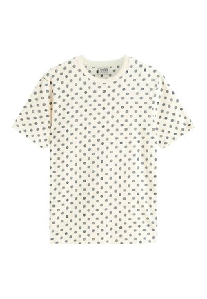 Witte T-shirt met korte mouwen met kleine zwarte zon- en cirkelvormige stippen die de stof gelijkmatig bedekken.