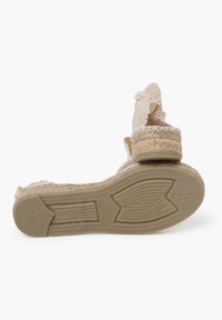 Sandalo espadrille con tomaia in beige intrecciato, soletta in corda texturizzata, suola in gomma e dettaglio a fiocco sulla cinghia.