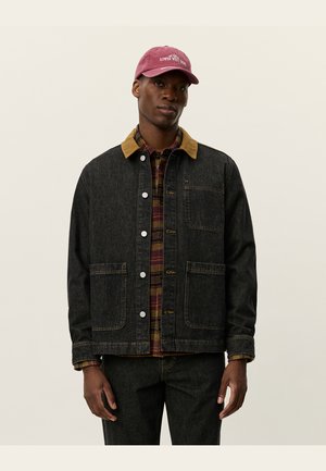 Mørk denimjakke med en brun kordfløjlskrave, der har to forlommer, knaplukning og en bordeauxternet skjorte under.
