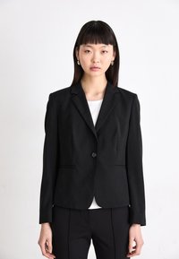Black tailored blazer with notched lapels, single button closure, and two front pockets. Smooth fabric, structured fit, and long sleeves.