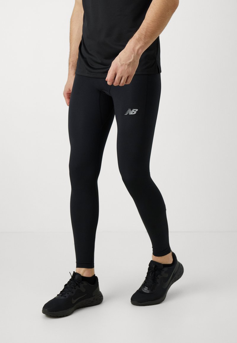 Leggings de sport noirs avec une coupe ajustée, fabriqués à partir d'un tissu lisse et extensible. Présentent un petit logo argenté sur la cuisse.