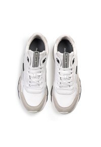 Zapatilla blanca con acentos en ante gris, diseño de cordones, superficie texturizada, cuello acolchado y logotipo en la lengüeta y en el lateral.