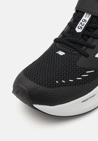 Chaussure de sport noire avec tige en mesh, surface texturée, accents blancs et marquage "FRESH FOAM" sur la semelle. Design moderne avec lacets.