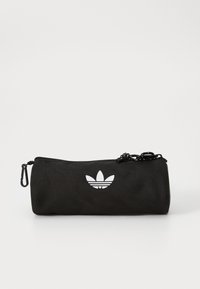 Fekete henger alakú táska tartós szövetből; fehér Adidas logóval, cipzáros zárással, húzózsinórral és karabinerrrel.