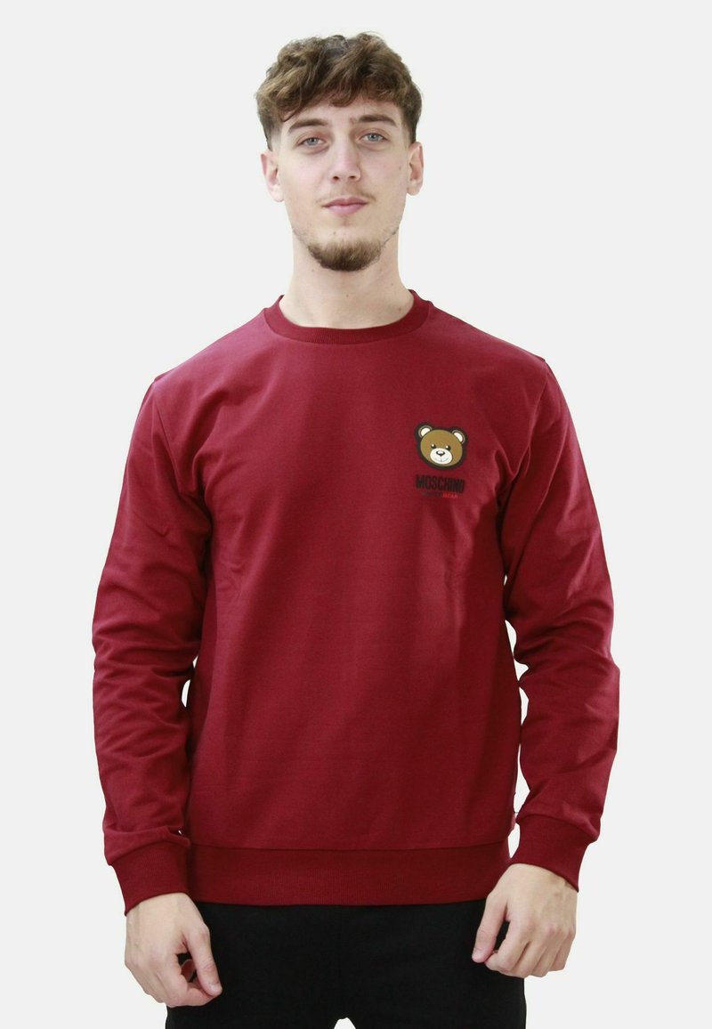 Felpa bordeaux con maniche lunghe, polsini a costine e piccolo logo orso con scritta "Moschino" sul davanti. Tessuto in misto cotone.